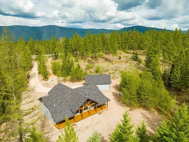 An aerial view of a house in the middle of a forest.