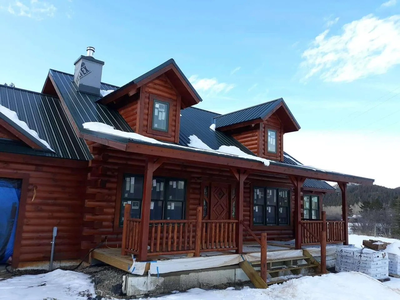 A log cabin with a porch and a black roof