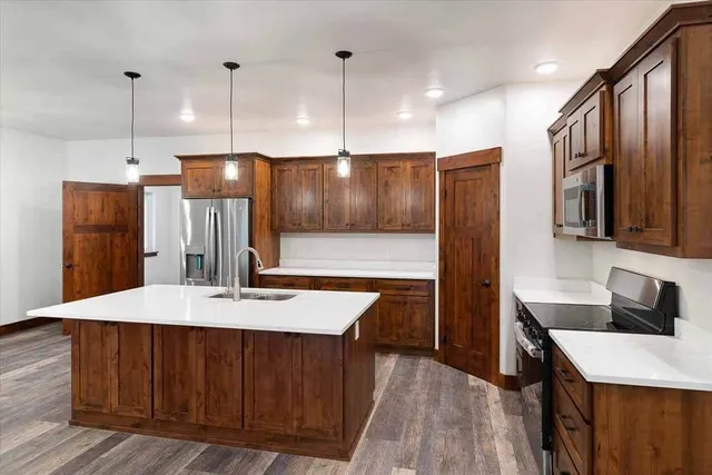 A kitchen with wooden cabinets, stainless steel appliances, and a large island.
