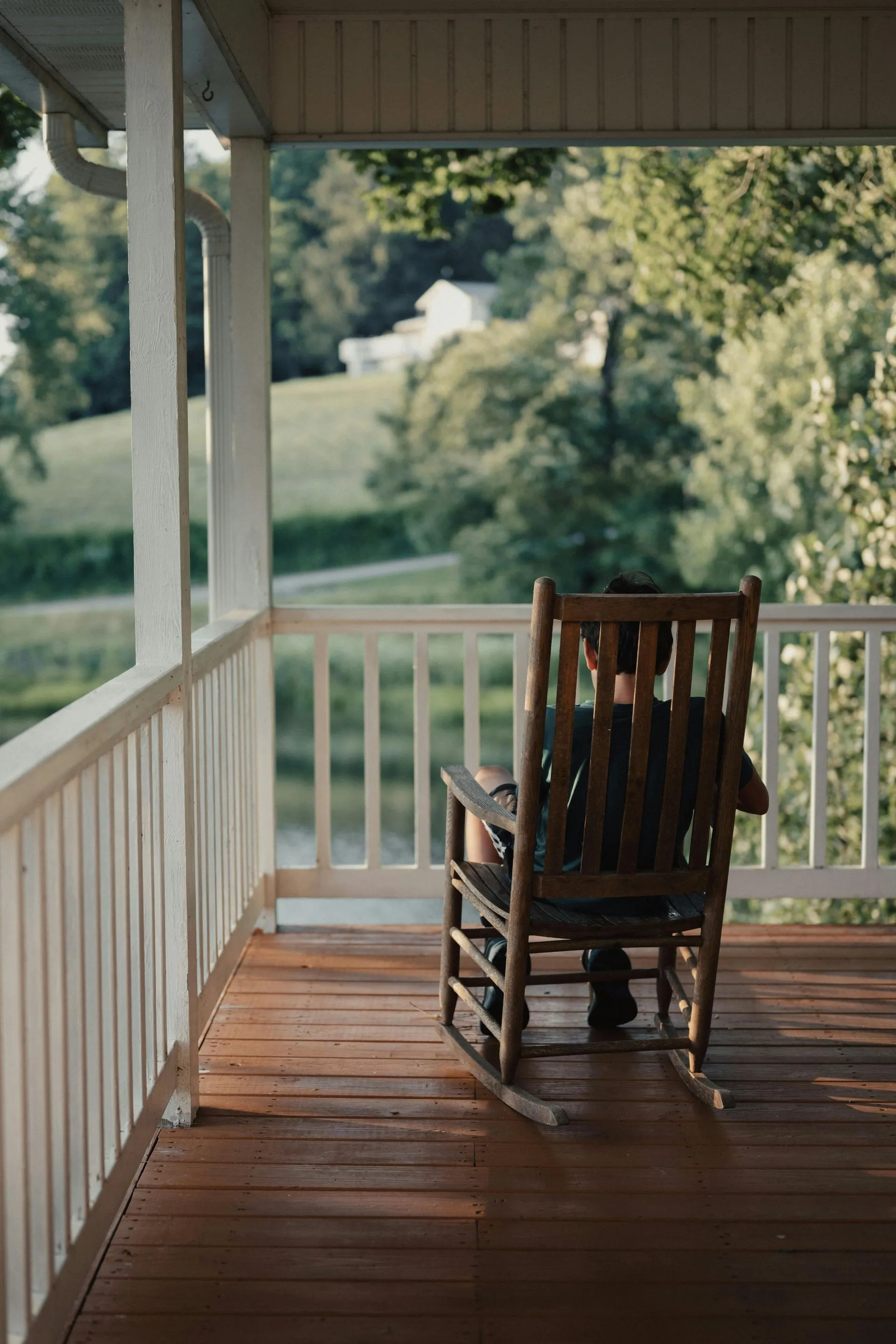 A man is sitting in a rocking chair on a porch.