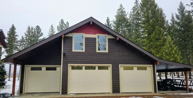 A large house with three garage doors and a large window.