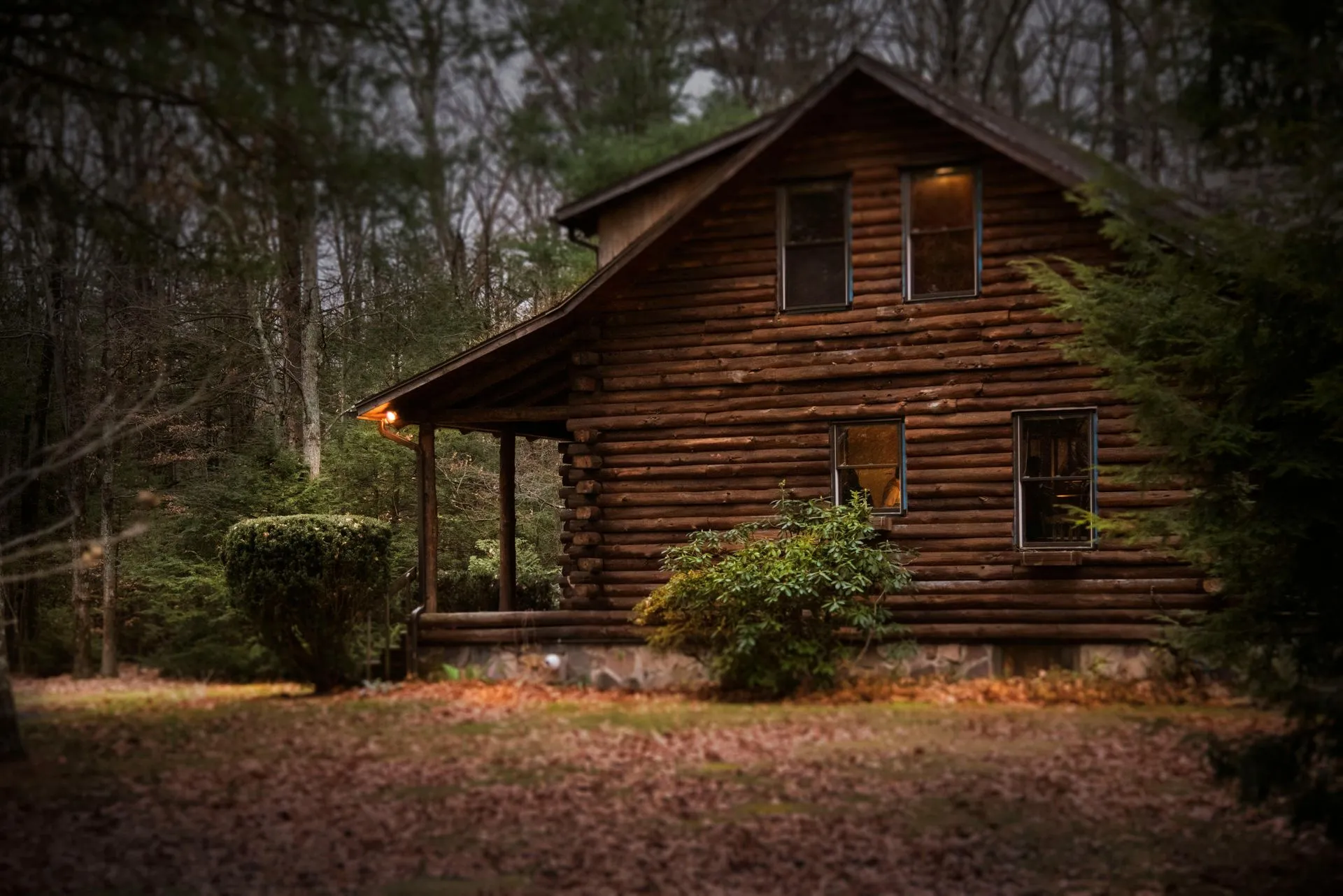 A log cabin with a green roof and a large deck