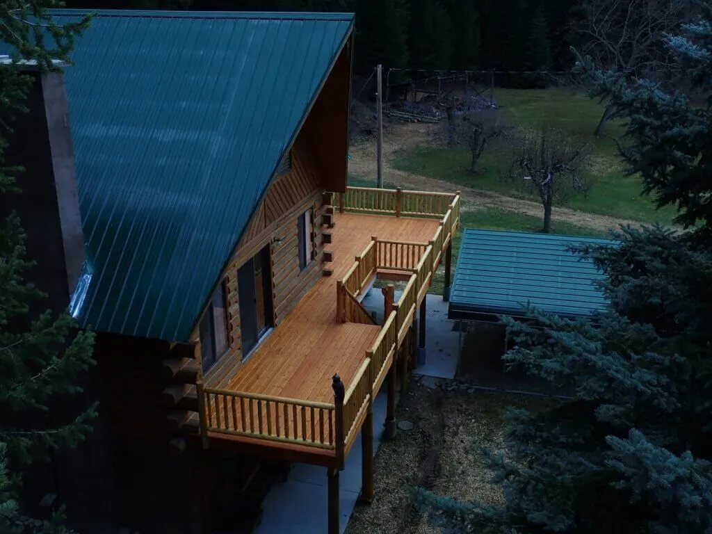 An aerial view of a log cabin with a large wooden deck